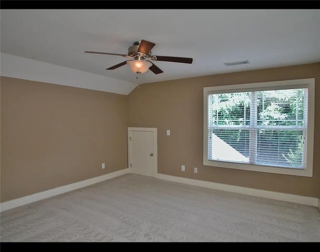 unfurnished room featuring carpet, a ceiling fan, vaulted ceiling, visible vents, and baseboards