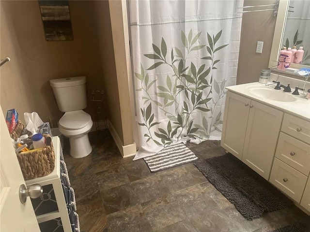 bathroom with stone finish floor, vanity, curtained shower, and toilet