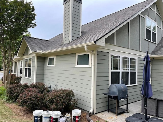 rear view of property featuring a chimney and a shingled roof