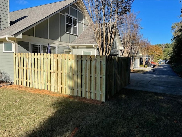 view of home's exterior with a yard, fence, and roof with shingles