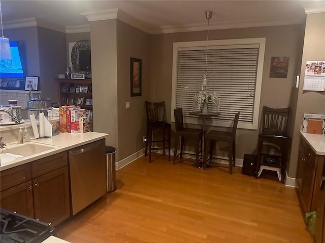 kitchen featuring ornamental molding, stainless steel dishwasher, and light wood-style floors