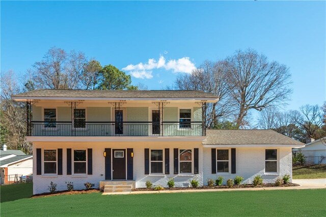 view of front of house with a balcony, a garage, and a front lawn