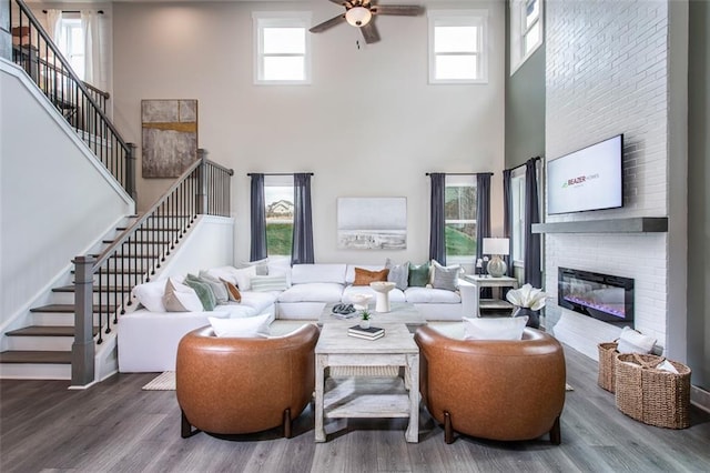 living room featuring wood-type flooring, plenty of natural light, and a towering ceiling