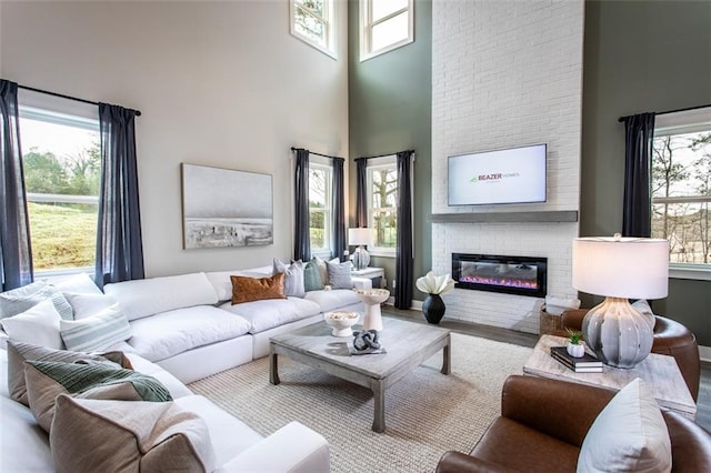 living room featuring a high ceiling, wood-type flooring, and a fireplace