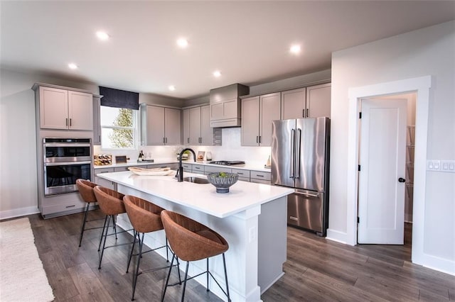 kitchen with a kitchen bar, appliances with stainless steel finishes, a center island with sink, and gray cabinets