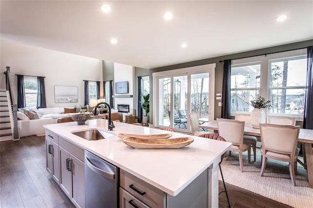 kitchen featuring dark hardwood / wood-style flooring, sink, gray cabinets, a kitchen island with sink, and stainless steel dishwasher