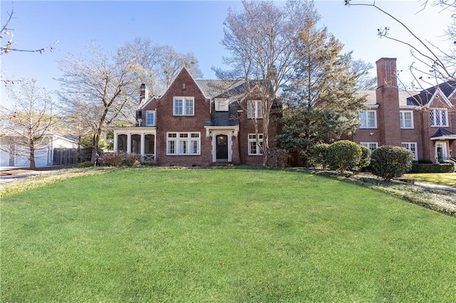 view of front of property with brick siding, a front yard, and a chimney