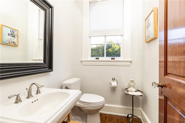 bathroom featuring wood finished floors, toilet, baseboards, and a sink