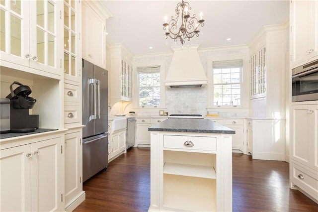 kitchen with a wealth of natural light, a notable chandelier, premium range hood, and appliances with stainless steel finishes