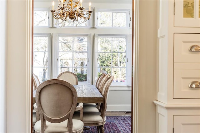 dining area featuring wood finished floors, a notable chandelier, baseboards, and plenty of natural light