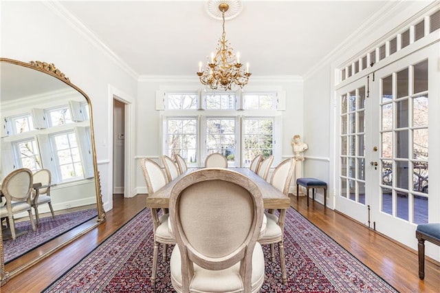 dining space with french doors, wood finished floors, a chandelier, and ornamental molding