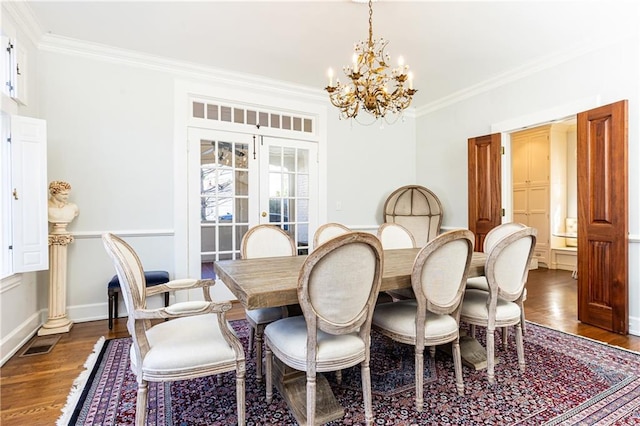 dining space with visible vents, dark wood-type flooring, an inviting chandelier, and crown molding