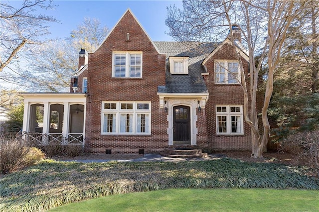 view of front of property with roof with shingles, a front yard, a sunroom, brick siding, and a chimney