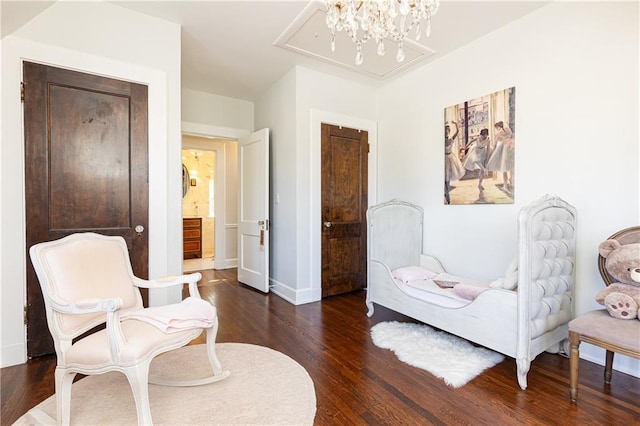 living area featuring a chandelier, baseboards, attic access, and wood finished floors