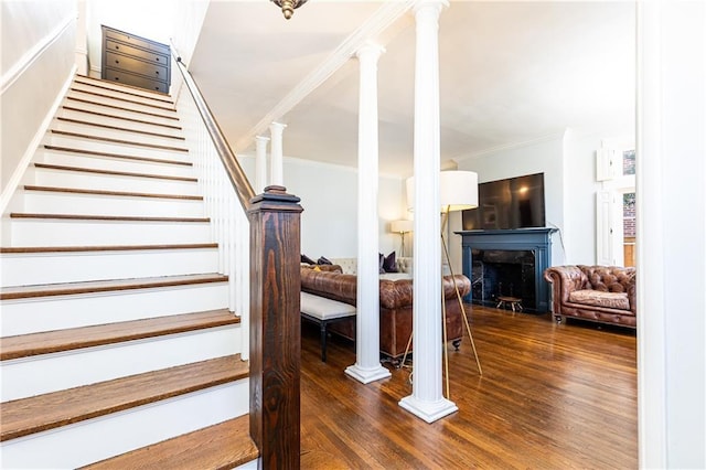 staircase featuring a fireplace, wood finished floors, and crown molding