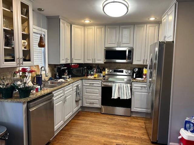 kitchen featuring stainless steel appliances, white cabinetry, dark stone countertops, and light hardwood / wood-style floors