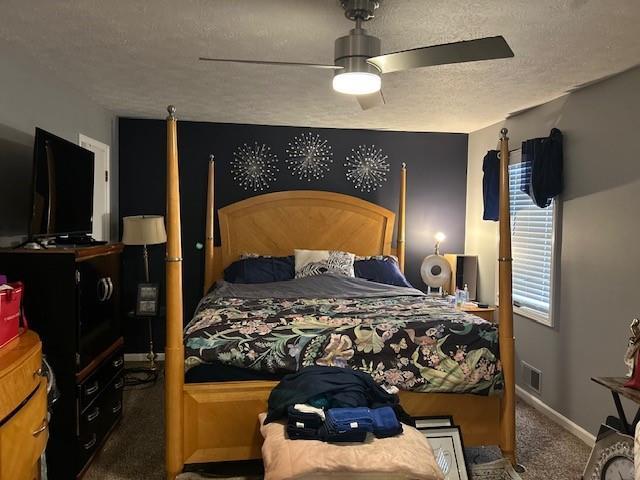 carpeted bedroom with ceiling fan and a textured ceiling