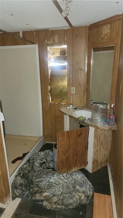 bathroom with sink, wooden walls, and a textured ceiling