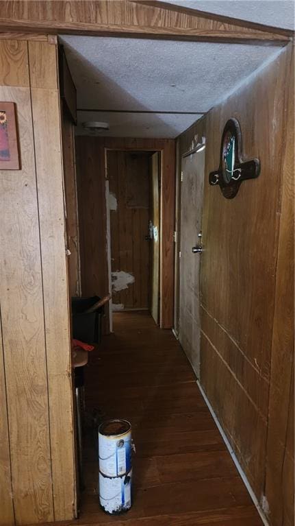 hall featuring dark hardwood / wood-style floors, a textured ceiling, and wood walls