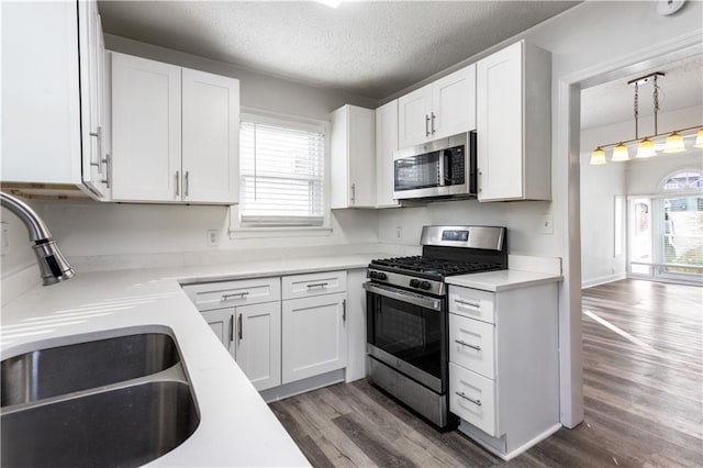 kitchen featuring hardwood / wood-style flooring, stainless steel appliances, sink, a textured ceiling, and white cabinets