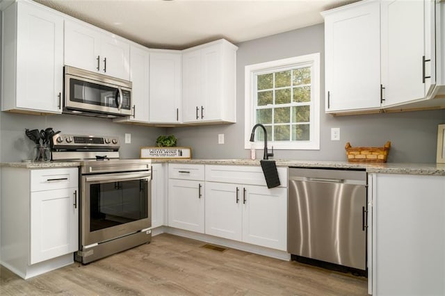 1912 Wax Rd, Aragon, GA 30113 - kitchen featuring appliances with stainless steel finishes, light wood finished floors, white cabinetry, and a sink