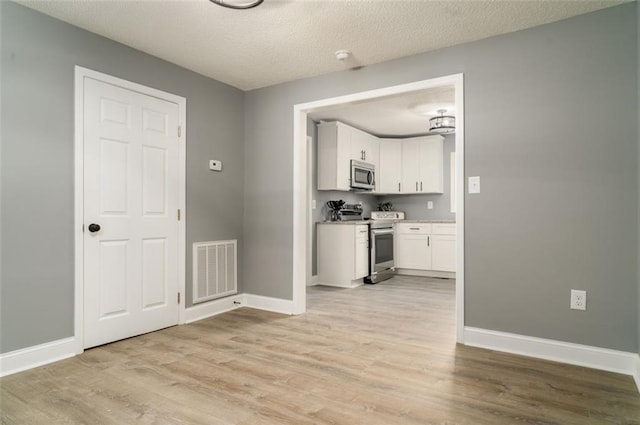 1912 Wax Rd, Aragon, GA 30113 - kitchen with stainless steel appliances, light wood-style floors, white cabinetry, baseboards, and a textured ceiling