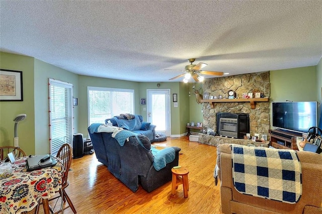 living room with a textured ceiling, ceiling fan, hardwood / wood-style floors, and a fireplace