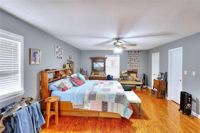 bedroom with hardwood / wood-style floors, ceiling fan, and a textured ceiling