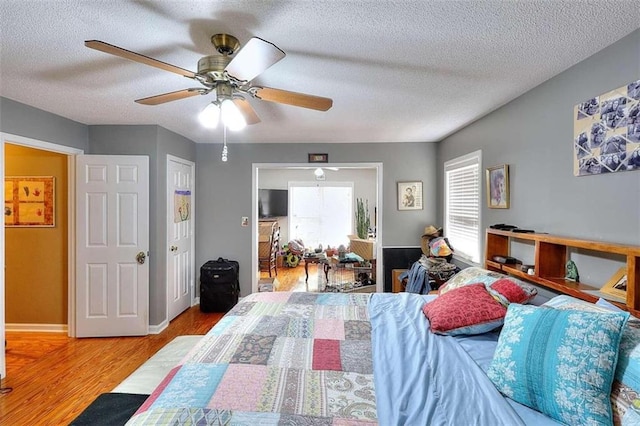 bedroom featuring hardwood / wood-style flooring, ceiling fan, and a textured ceiling