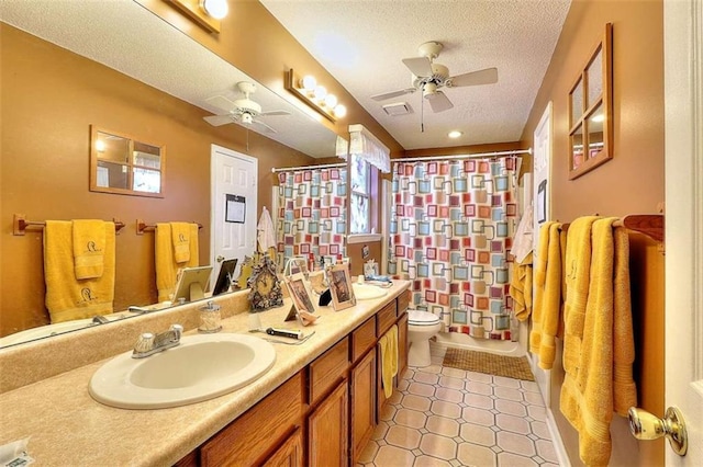 bathroom featuring double vanity, tile flooring, a textured ceiling, ceiling fan, and toilet