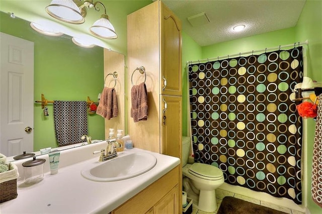 bathroom featuring oversized vanity, tile floors, toilet, and a textured ceiling