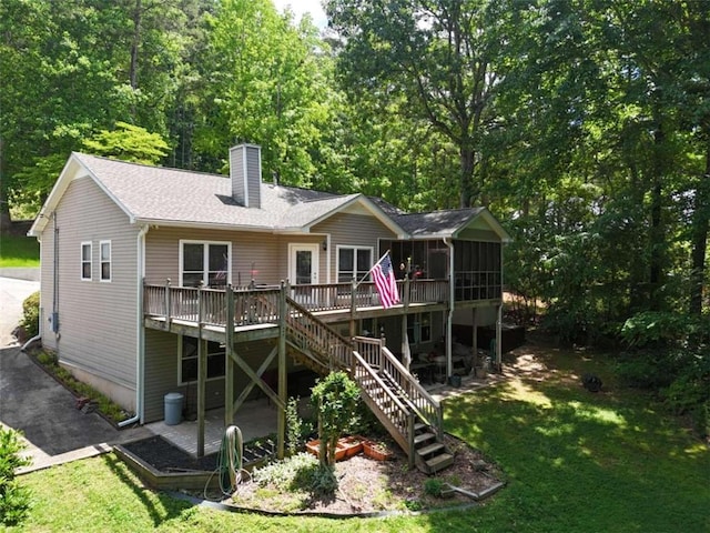 rear view of house with a wooden deck, a sunroom, and a lawn