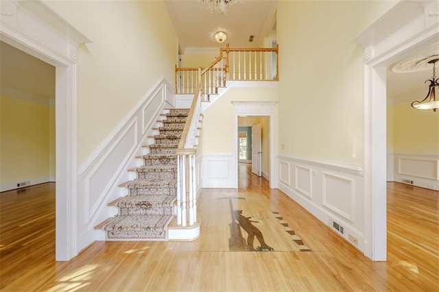 foyer entrance with crown molding, an inviting chandelier, and hardwood / wood-style flooring