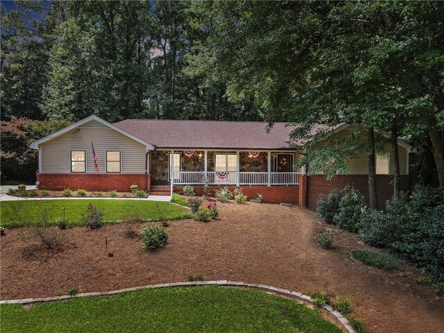 ranch-style home featuring covered porch and a front yard