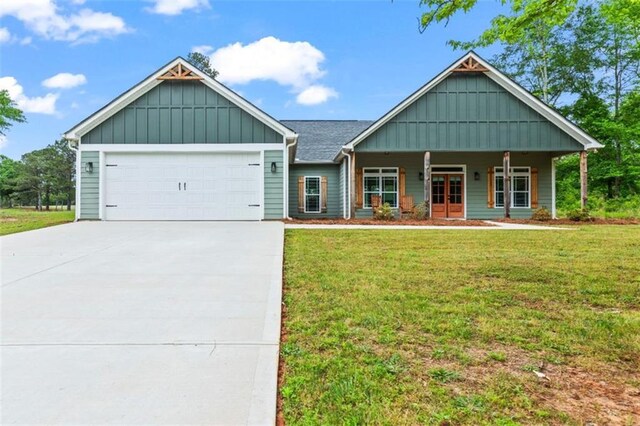 craftsman-style home with a front yard, board and batten siding, an attached garage, driveway, and a porch