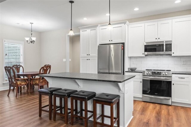 kitchen featuring dark countertops, a kitchen breakfast bar, stainless steel appliances, and wood finished floors