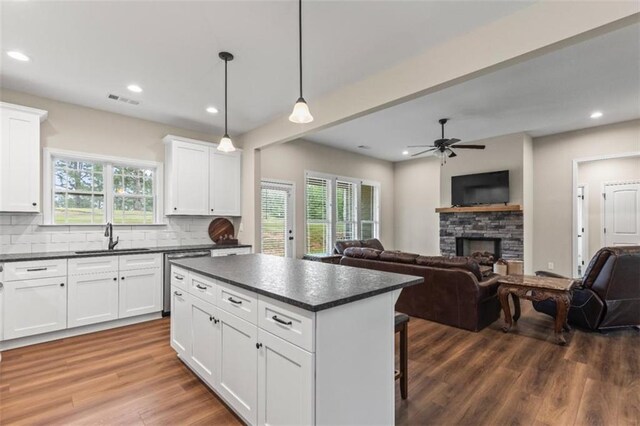 kitchen featuring visible vents, dark countertops, dishwasher, a sink, and open floor plan