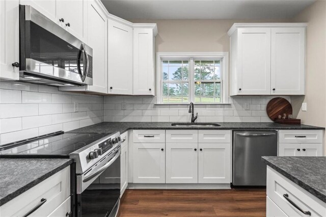kitchen featuring decorative backsplash, a sink, white cabinets, stainless steel appliances, and dark wood-type flooring