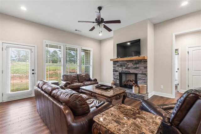 living room featuring visible vents, wood finished floors, a fireplace, baseboards, and ceiling fan