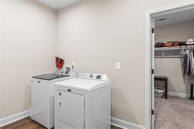 clothes washing area with washing machine and clothes dryer, laundry area, visible vents, and baseboards