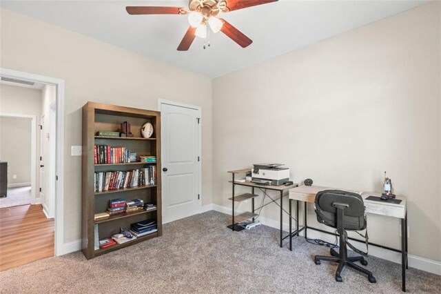 carpeted office space with baseboards, a ceiling fan, and visible vents