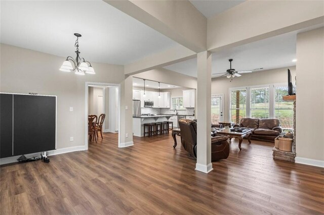 living room featuring baseboards, recessed lighting, dark wood-type flooring, and ceiling fan with notable chandelier