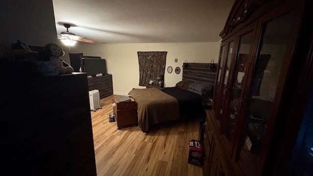 bedroom with radiator heating unit and light wood-style flooring