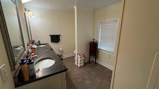 bathroom featuring ornamental molding, a sink, baseboards, and double vanity