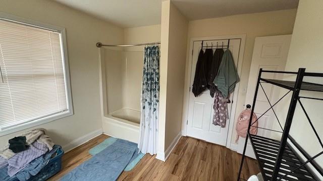 bathroom featuring shower / bath combo, baseboards, and wood finished floors