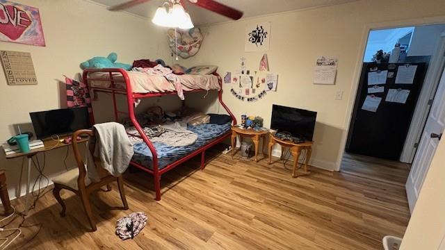 bedroom featuring refrigerator, ceiling fan, baseboards, and wood finished floors