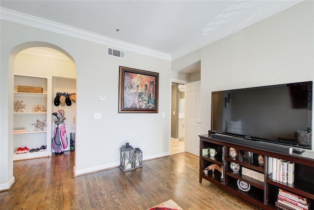 living room with crown molding, visible vents, arched walkways, and wood finished floors