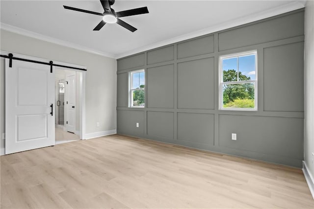 1698 Cunningham Rd SW, Marietta, GA 30008 - unfurnished bedroom with a decorative wall, a barn door, crown molding, light wood-style floors, and baseboards