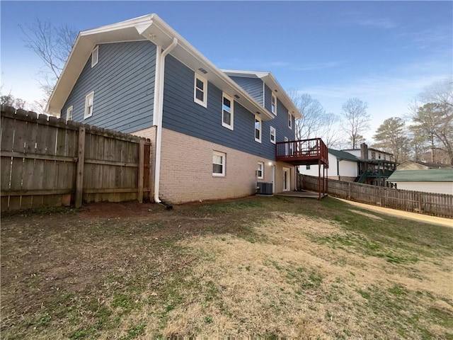 rear view of house with a wooden deck, a lawn, and cooling unit