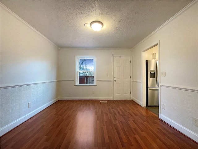 spare room featuring ornamental molding, dark hardwood / wood-style floors, and a textured ceiling